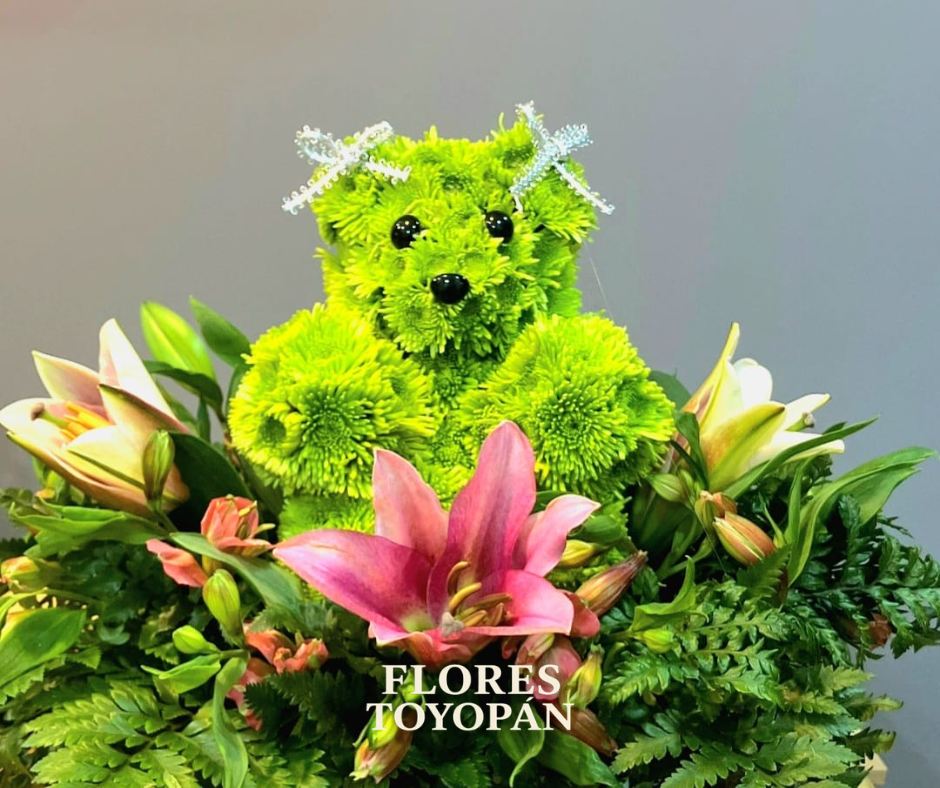 Arreglo floral que consiste en un oso de volor verde, decorado con flores varias